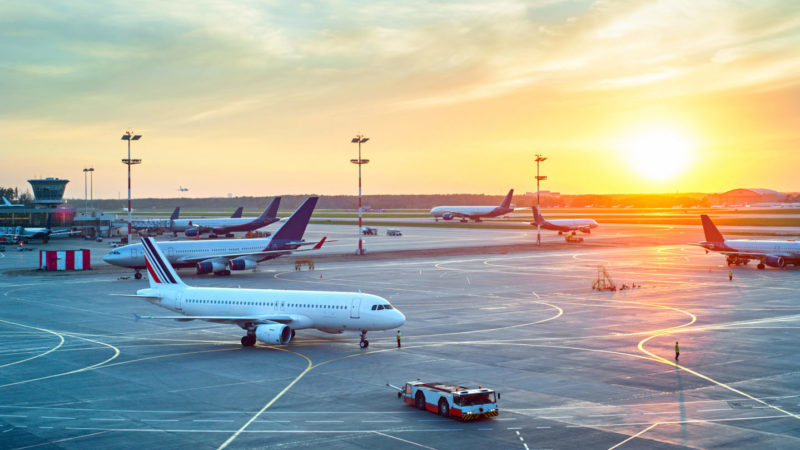 Sunrise over airplanes on airport tarmac