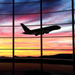 Airplane takes off in front of airport at sunset
