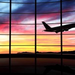 Airplane takes off in front of airport at sunset